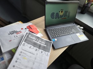 Na zdjęciu widzimy komputer kartki i plakat na biurku.