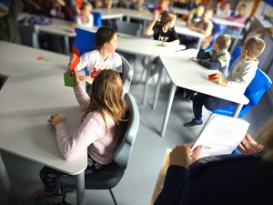 Na zdjęciu widzimy grupę uczniów, którzy trzymają kartki koloru czerwonego w ręce oraz policjantkę, trzymającą scenariusz prelekcji.