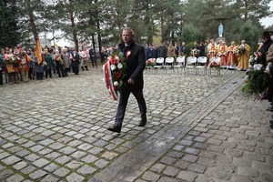 Na zdjęciu mężczyzna niesie wiązankę kwiatów