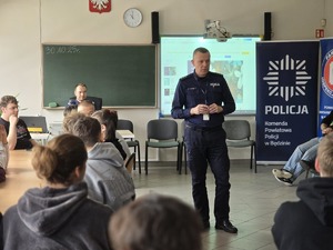 Na zdjęciu umundurowany policjant, który przemawia do młodzieży podczas debaty.