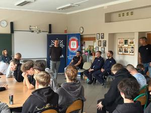 Na zdjęciu mężczyzna, który przemawia do grupy młodzieży w sali lekcyjnej.