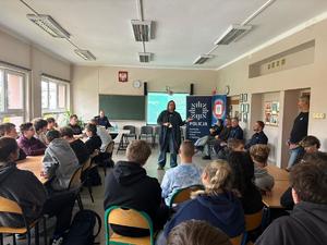 Na zdjęciu kobieta w sali lekcyjnej debatuje z młodzieżą.