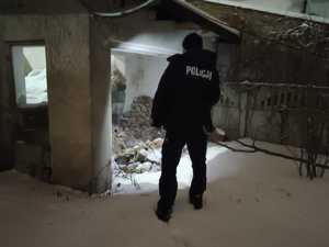 Na zdjęciu policjant kontroluje pustostany w zimę.