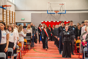 Na zdjęciu widzimy maszerujących uczniów oddziału mundurowego na sali gimnastycznej.