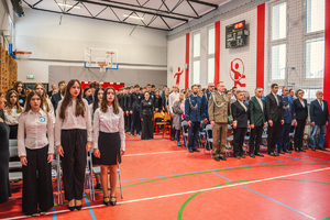 Zdjęcie grupowe, na którym uczestnicy uroczystości stoją na baczność podczas śpiewania hymnu.