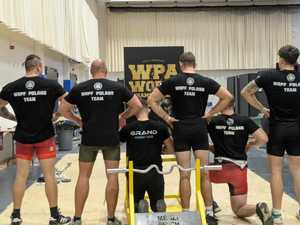 Na zdjęciu grupa mężczyzn na zawodach siłowych stoją plecami