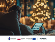 Osoba siedząca wieczorem na kanapie w przytulnie oświetlonym wnętrzu, przegląda tablet; w tle rozmyte światła choinki tworzą świąteczny nastrój.