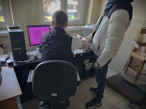 Na zdjęciu policyjny technik kryminalistyki pobiera odciski palców od mężczyzny.