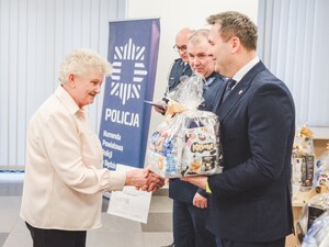Komendant Powiatowy Policji w Będzinie oraz Starosta Będziński wyróżniają pracowników z okazji Święta Służby Cywilnej, starosta wręcza upominek.