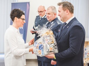 Komendant Powiatowy Policji w Będzinie oraz Starosta Będziński wyróżniają pracowników z okazji Święta Służby Cywilnej, starosta wręcza upominek.