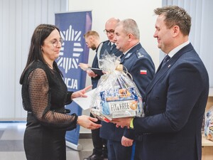 Komendant Powiatowy Policji w Będzinie oraz Starosta Będziński wyróżniają pracowników z okazji Święta Służby Cywilnej, starosta wręcza upominek.