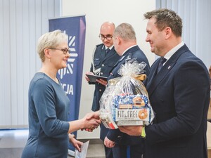 Komendant Powiatowy Policji w Będzinie oraz Starosta Będziński wyróżniają pracowników z okazji Święta Służby Cywilnej, starosta wręcza upominek.