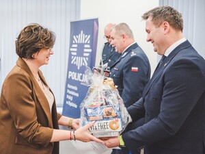 Komendant Powiatowy Policji w Będzinie oraz Starosta Będziński wyróżniają pracowników z okazji Święta Służby Cywilnej, starosta wręcza upominek.