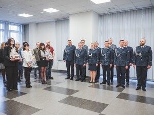 Zdjęcie grupowe kadry kierowniczej będzińskiej Policji i pracowników cywilnych Policji w pomieszczeniu.