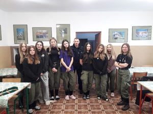 Zdjęcie grupowe, policjant z grupą młodzieży podczas spotkania dotyczącego bezpiecznych ferii.