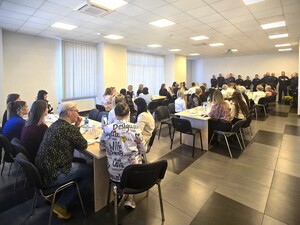 Zdjęcie grupowe. Policjanci w mundurach stoją, a kobiety siedzą przy stołach.