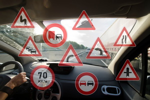 Na grafice widać przednią szybę samochodu od wewnętrznej strony pojazdu a na niej umieszczone zostały znaki zakazu