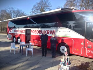 Na zdjęciu policjantka i policjant stoją przed autokarem.