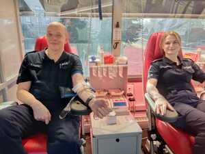 Na zdjęciu policjant i policjantka na fotelu podczas oddawania krwi.