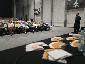 Na zdjęciu występujący przed grupą seniorów pracownik banku.