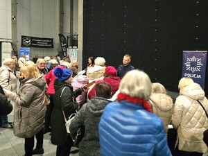 Zdjęcie grupowe seniorów podchodzących to policjantów i pracowników banku.