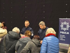 Na zdjęciu policjanci rozmawiają z grupą seniorów.