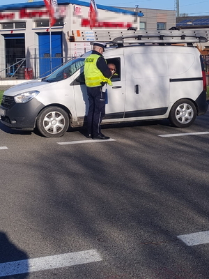 Na zdjęciu umundurowany policjant bada trzeźwość kierującemu, który jedzie samochodem.