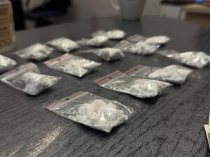 Na zdjęciu narkotyki w postaci białego proszku w woreczkach strunowych rozłożone na biurku.