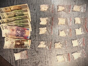 Na zdjęciu pieniądze oraz narkotyki w postaci białego proszku w woreczkach strunowych rozłożone na biurku.