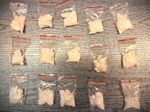 Na zdjęciu narkotyki w postaci białego proszku w woreczkach strunowych rozłożone na biurku.