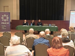 Zdjęcie grupowe podczas debaty na temat bezpieczeństwa seniorów na sali konferencyjnej. Widzimy seniorów, policjantów i zaproszonych prelegentów.