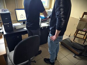 Na zdjęciu zatrzymanemu są pobierane odciski palców przez technika kryminalistyki.