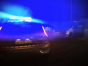 Na zdjęciu policyjny radiowóz i inny samochód osobowy w porze nocnej.