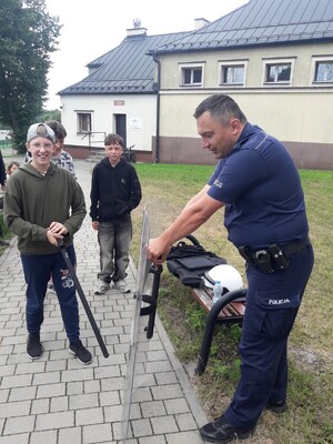 Na zdjęciu policjant pokazuje młodzieży tarczę policyjną.