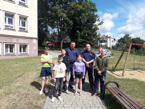 Zdjęcie grupowe dwóch policjantów z młodzieżą na dworze.