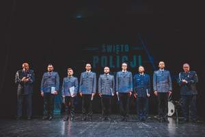 Zdjęcie grupowe w teatrze przedstawiające policjantów występujących do mianowania na scenie z Zastępcą Komendanta Wojewódzkiego Policji w Katowicach oraz Komendantem Powiatowym Policji w Będzinie.
