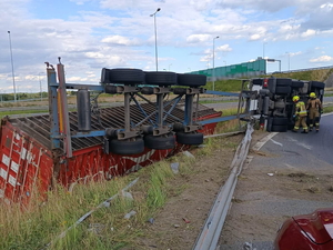 Na zdjęciu widzimy przewróconą ciężarówkę na łuku drogi oraz służby w akcji.