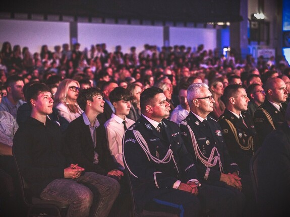 Zdjęcie grupowe podczas wojewódzkiego rozpoczęcia roku szkolnego w będzińskiej hali sportowej. Na zdjęciu policjanci i strażacy i widzowie. Widzimy Zastępcę Komendanta Powiatowego Policji w Będzinie oraz Komendanta Wojewódzkiego Policji w Katowicach.