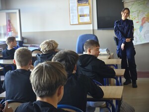 Na zdjęciu policjantka podczas lekcji rozmawia z uczniami o zagrożeniach i prowadzi zajęcia.